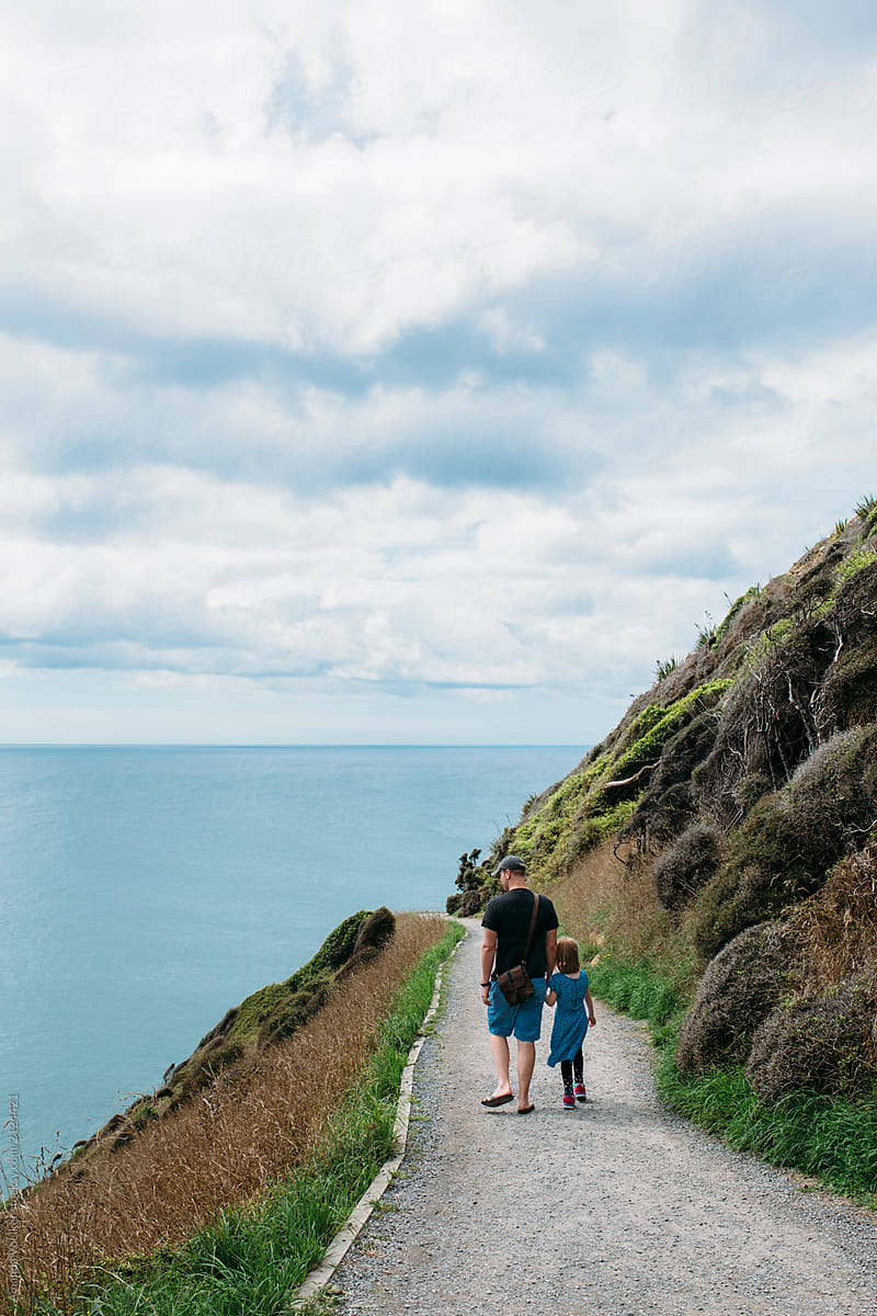 Back View of Father and daughter walking along a coastal cliff path