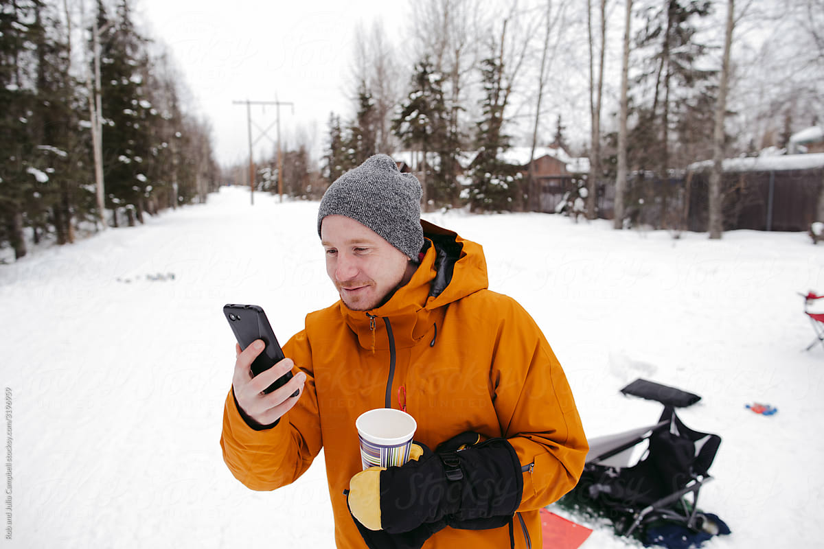 Man using cell phone for a video call in the snow.