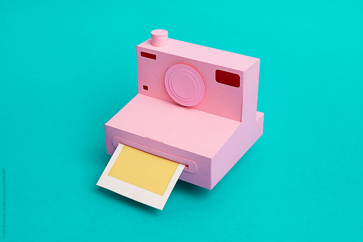 Retro instant camera made with paper in a turquoise background with copy space