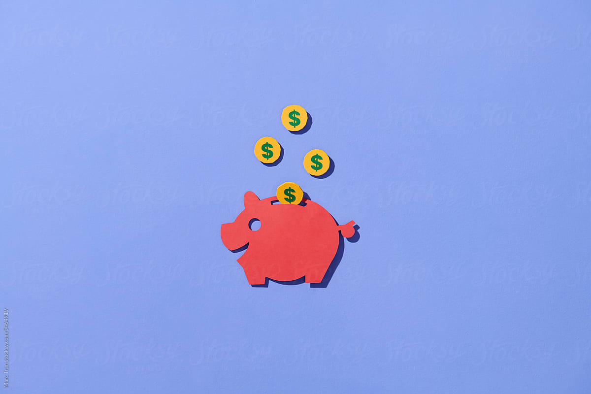 red piggy bank with coins falling into slot isolated on blue.