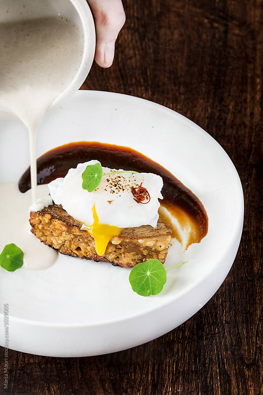 Crispy Iberian bacon with poached egg and garlic sauce with coconut and hazelnuts