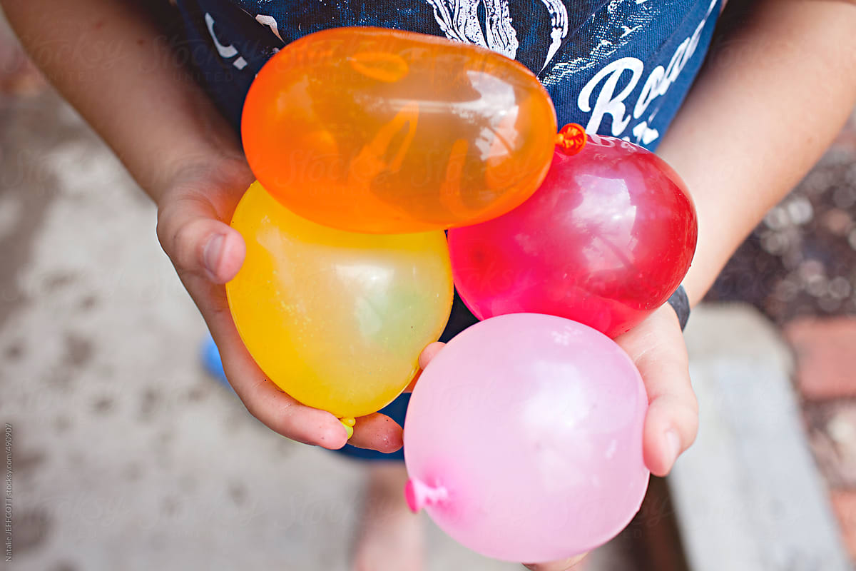 close up of child holding colourful water balloons