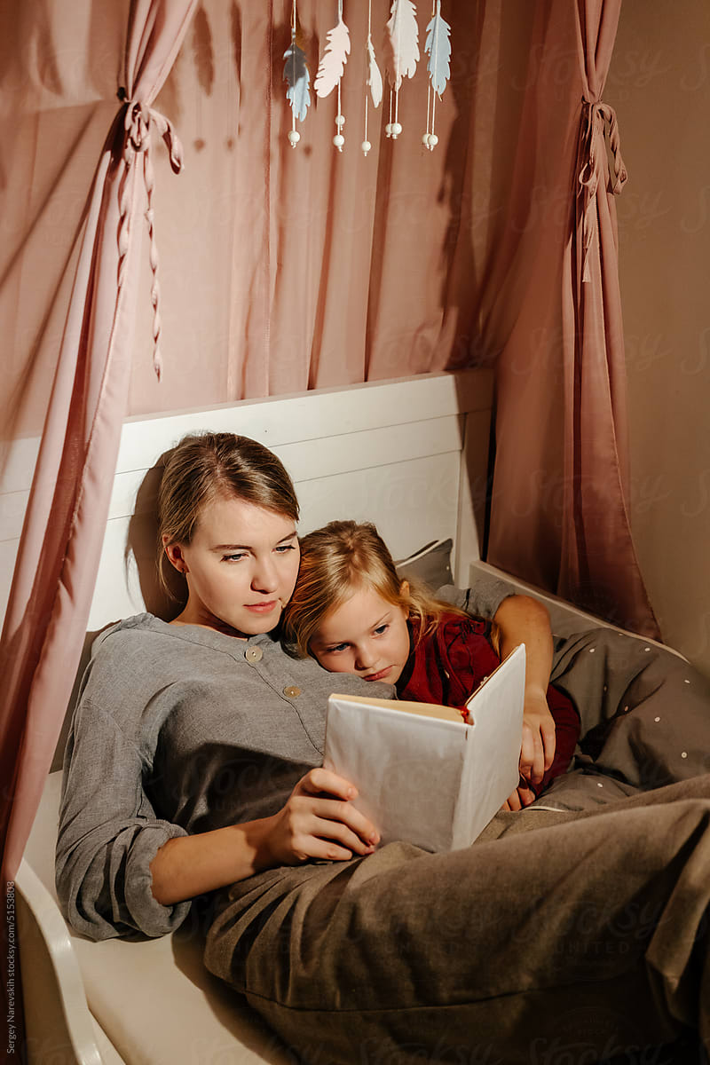 Mother and daughter reading book before sleep
