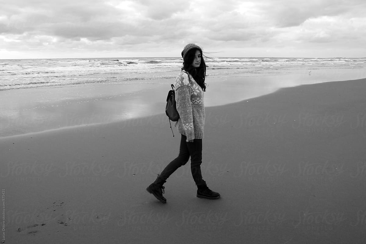 Black and white - woman walking along the beach in winter