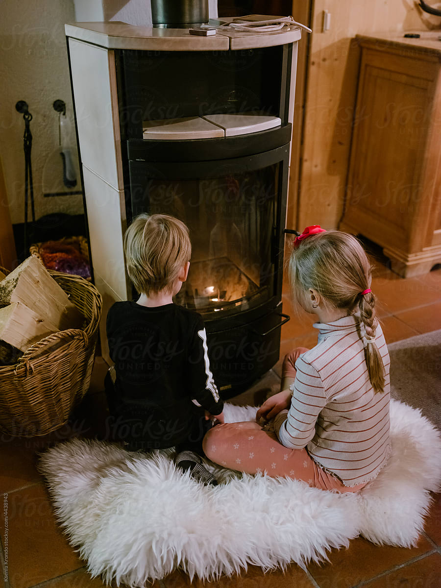Siblings getting warm at the fireplace