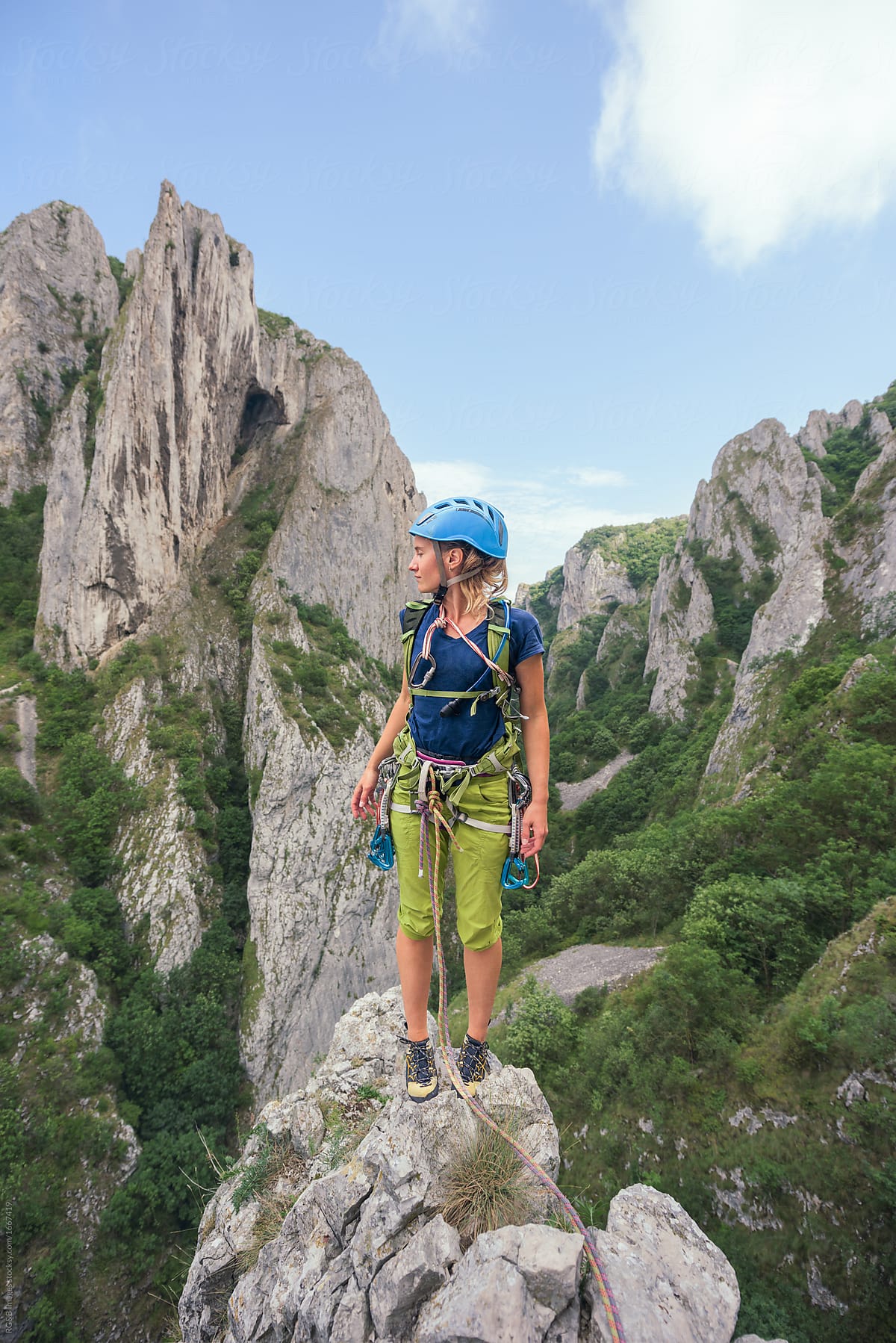 Female rock climber standing on the top of a cliff