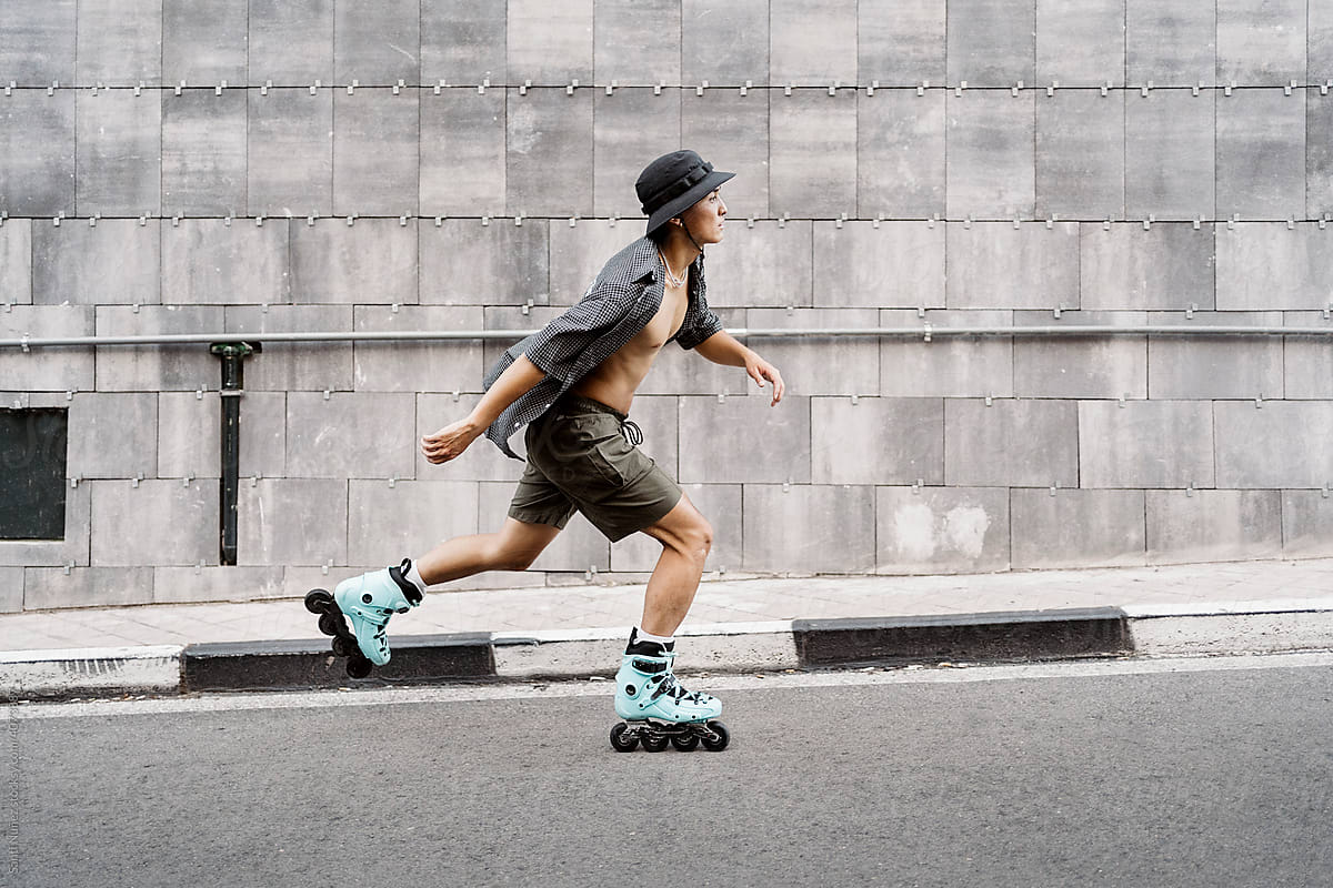 Side view of a young man roller skating on the street in the city