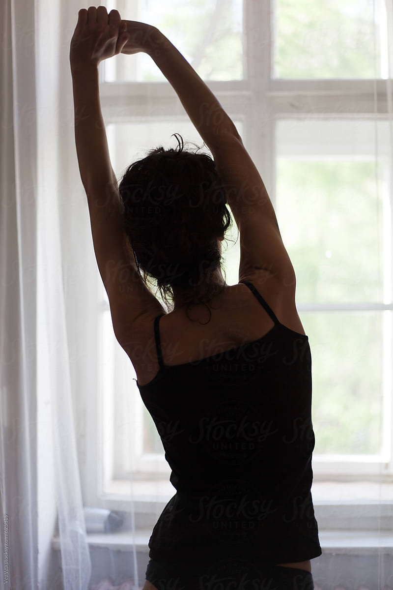 Woman in black underwear standing near the window.