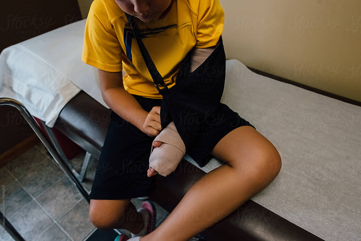 Boy sitting in doctor\'s office with a broken arm.