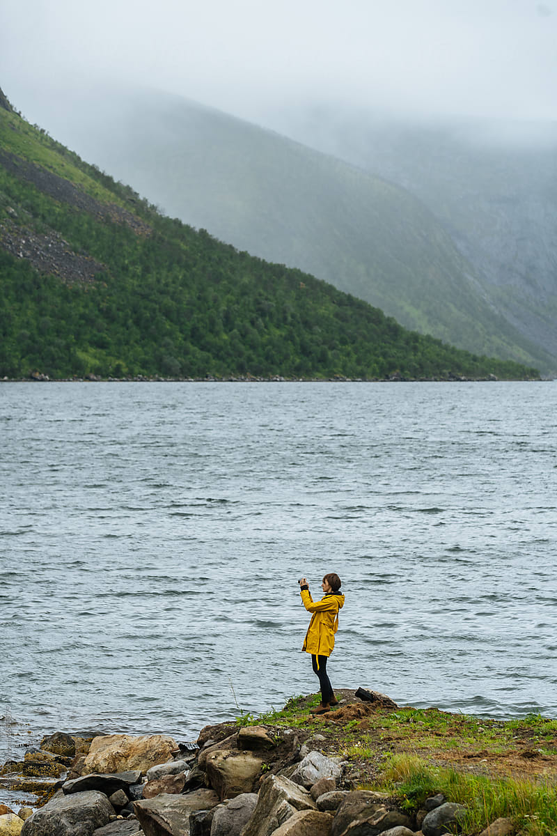 Woman in raincoat taking picture of sea
