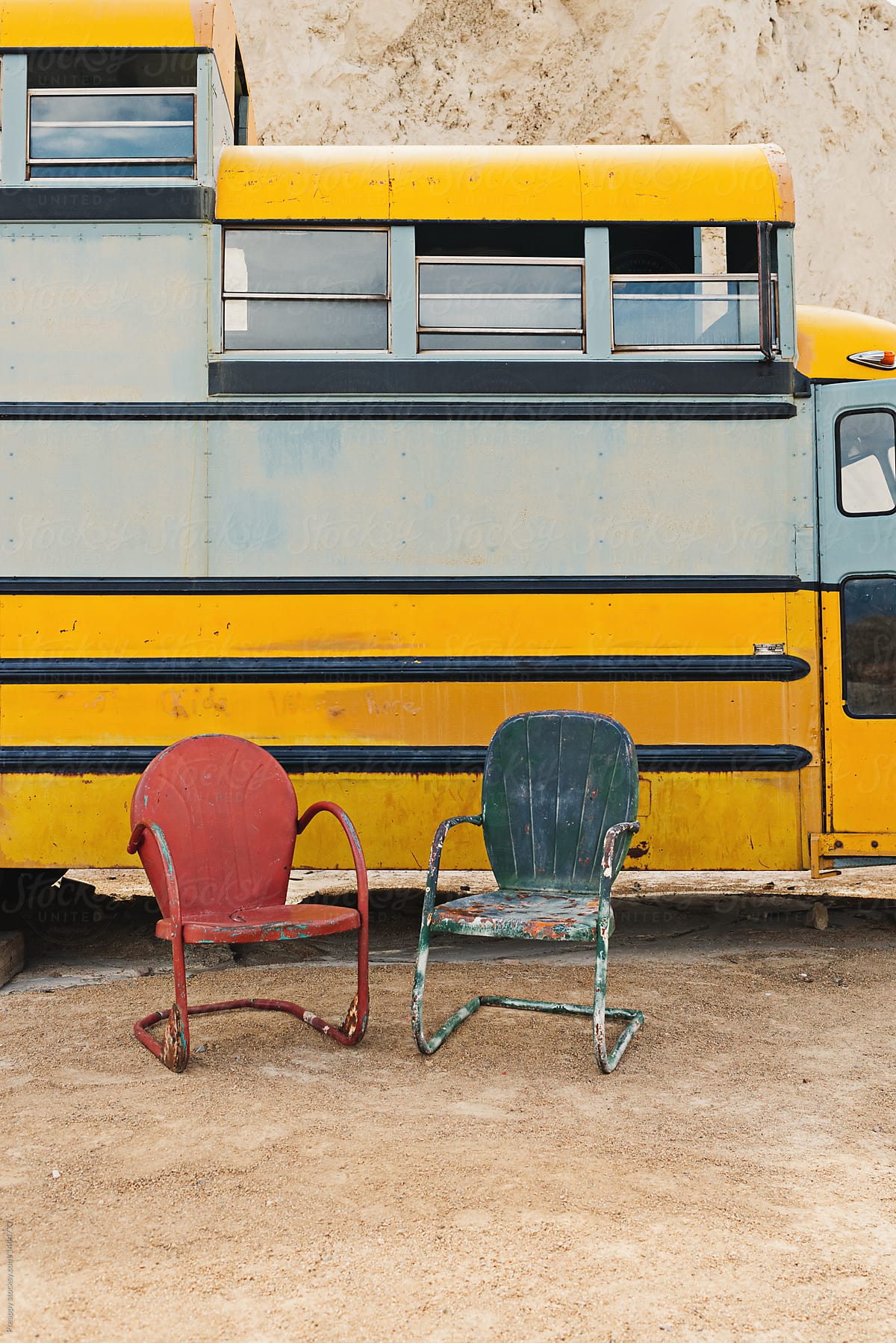Two metal chairs outdoors against school bus