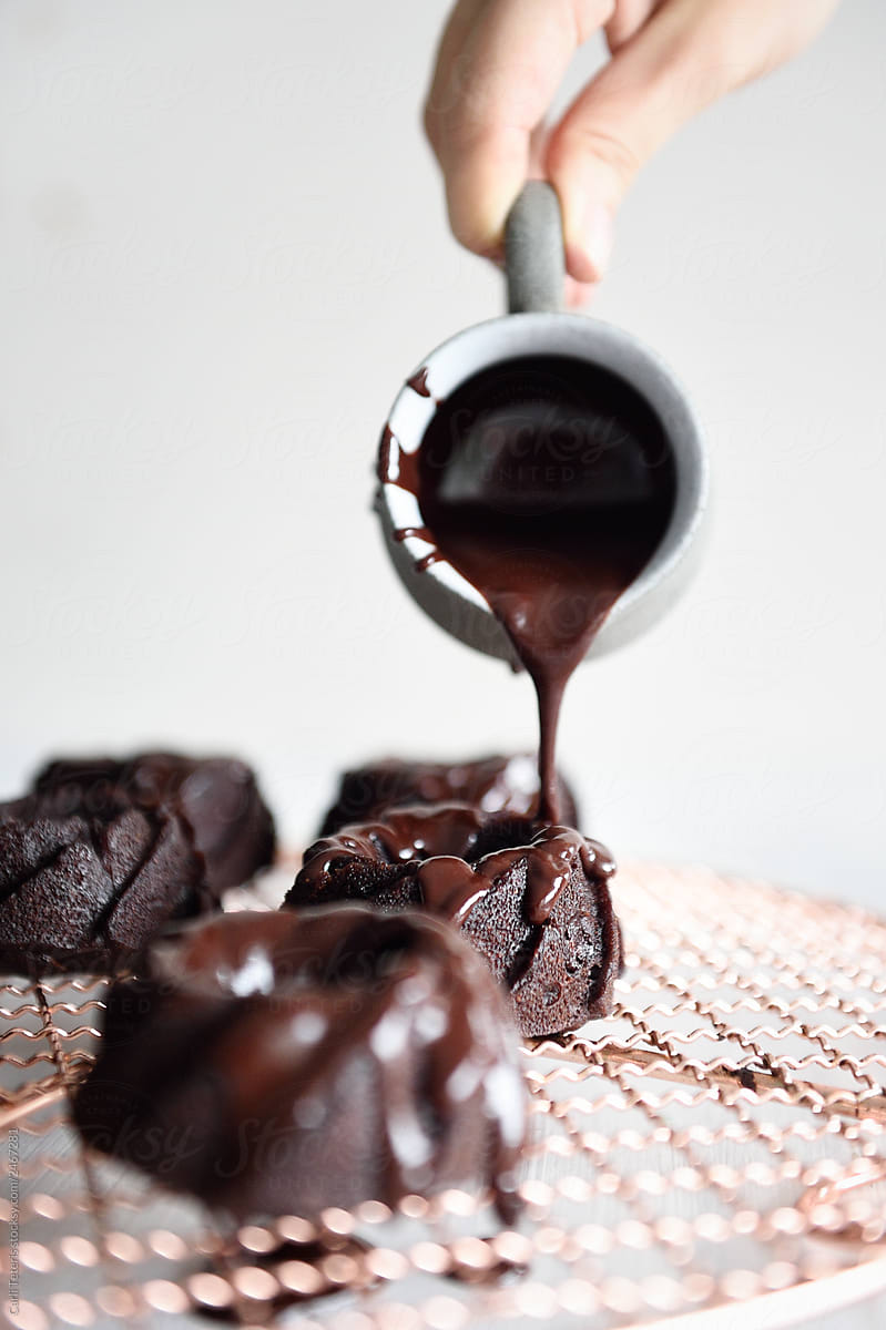 Pouring chocolate glaze over mini bundt cakes
