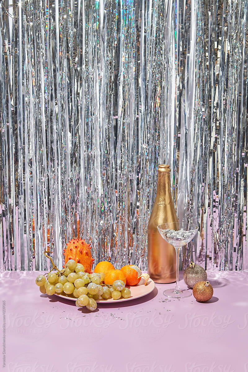 Festive table with bottle of champagne, glass and fruits