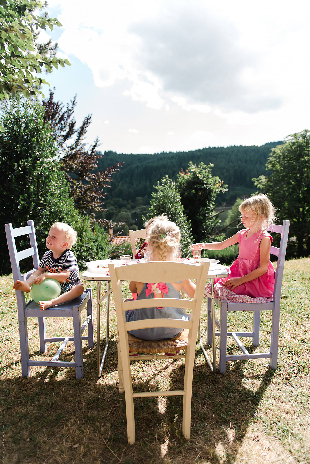 four children eating at table outside in the sun