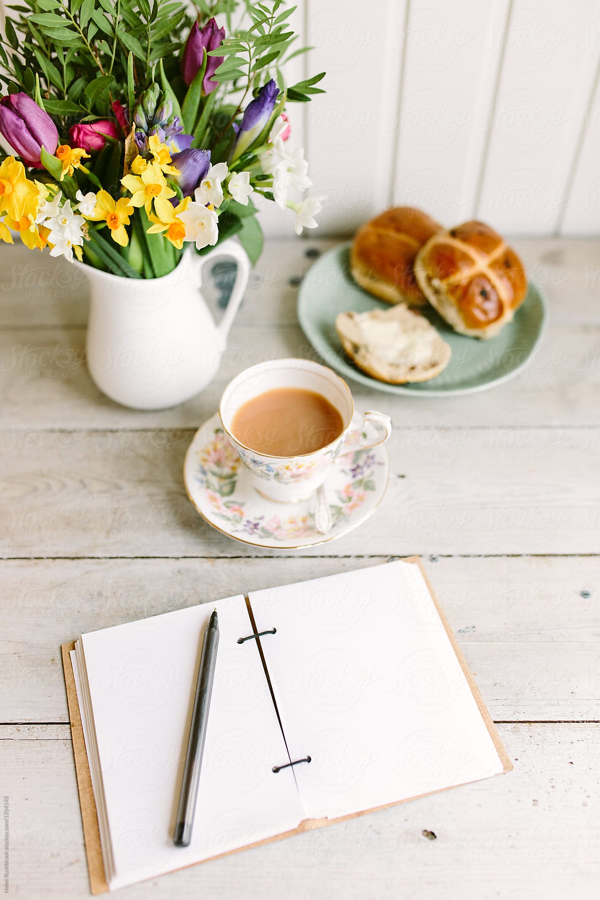 Hot cross buns, spring flowers and a cup of tea, with a blank notebook