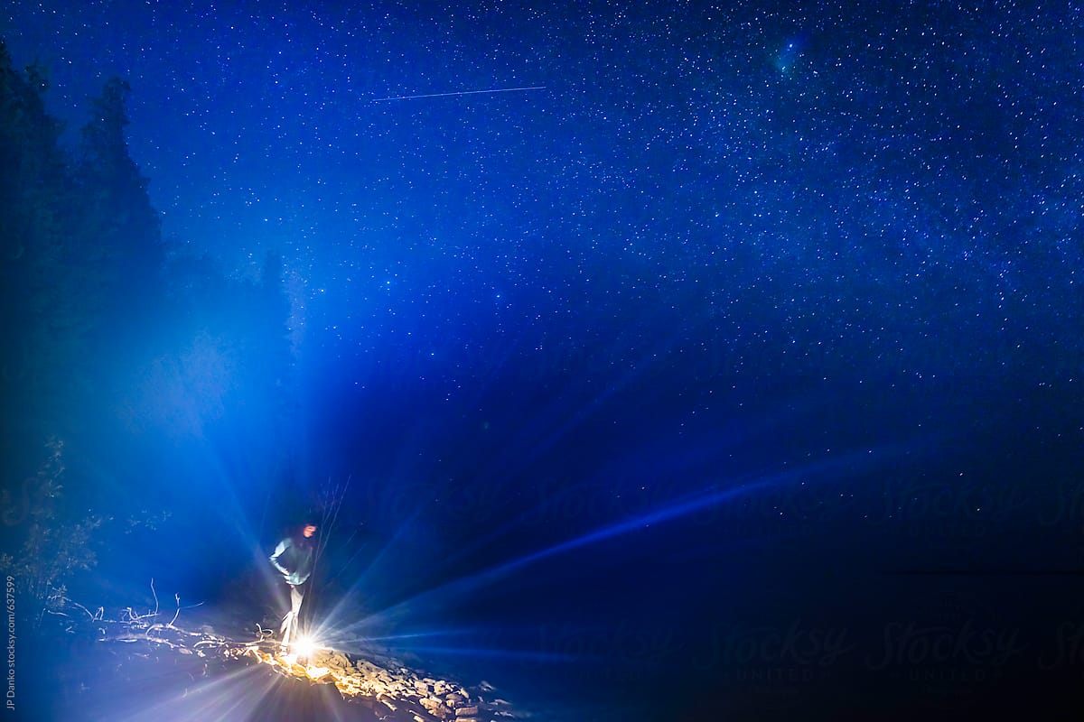 Woman Illuminated By Flashlight Lantern Camping On Northern Beach Under Milkyway Stars