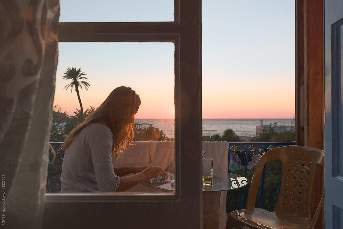Young woman on the balcony with beautiful seascape during sunset