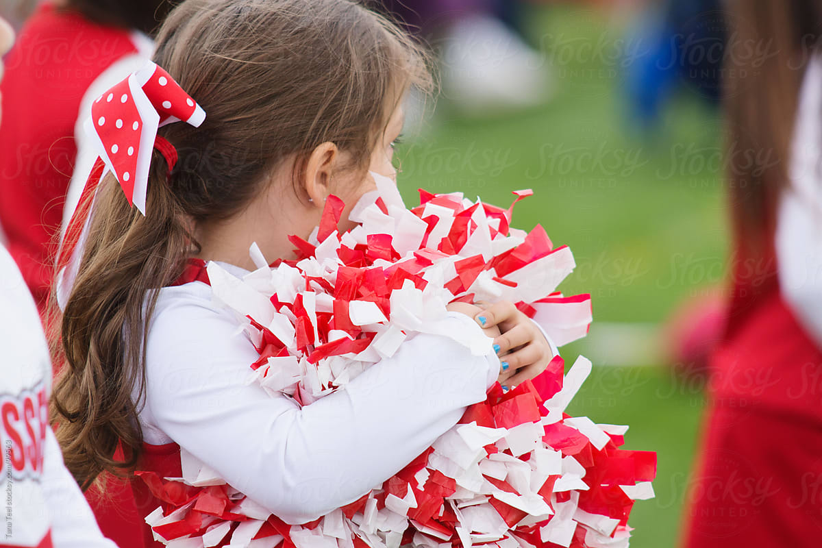 A young cheerleader watches the football game