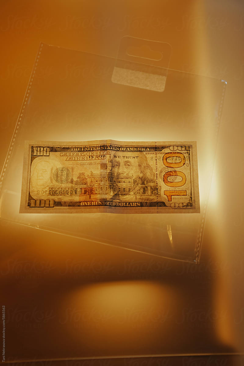 One hundred dollar banknote in plastic in gold light