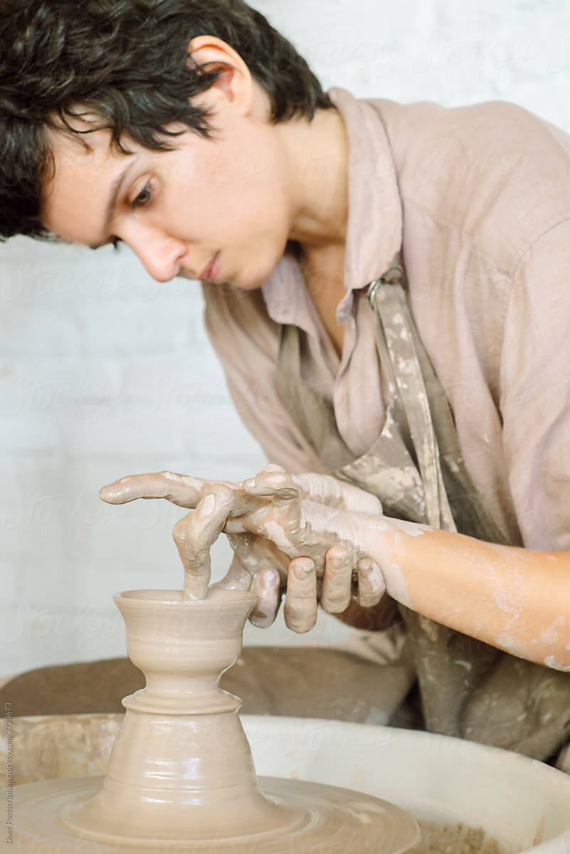 Stylish girl makes a cup of clay on a potter\'s wheel