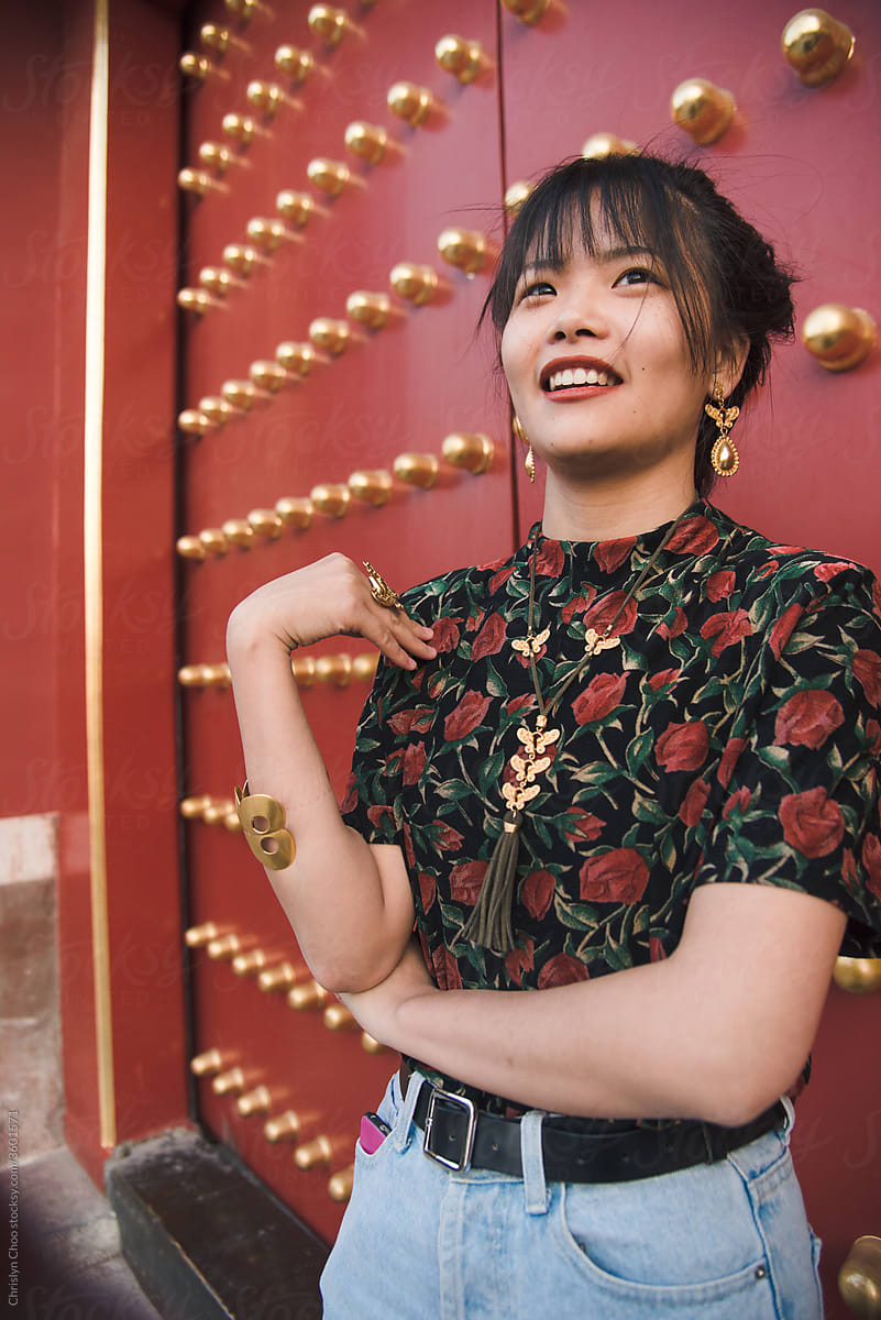 Stylish woman standing by red Chinese temple doors