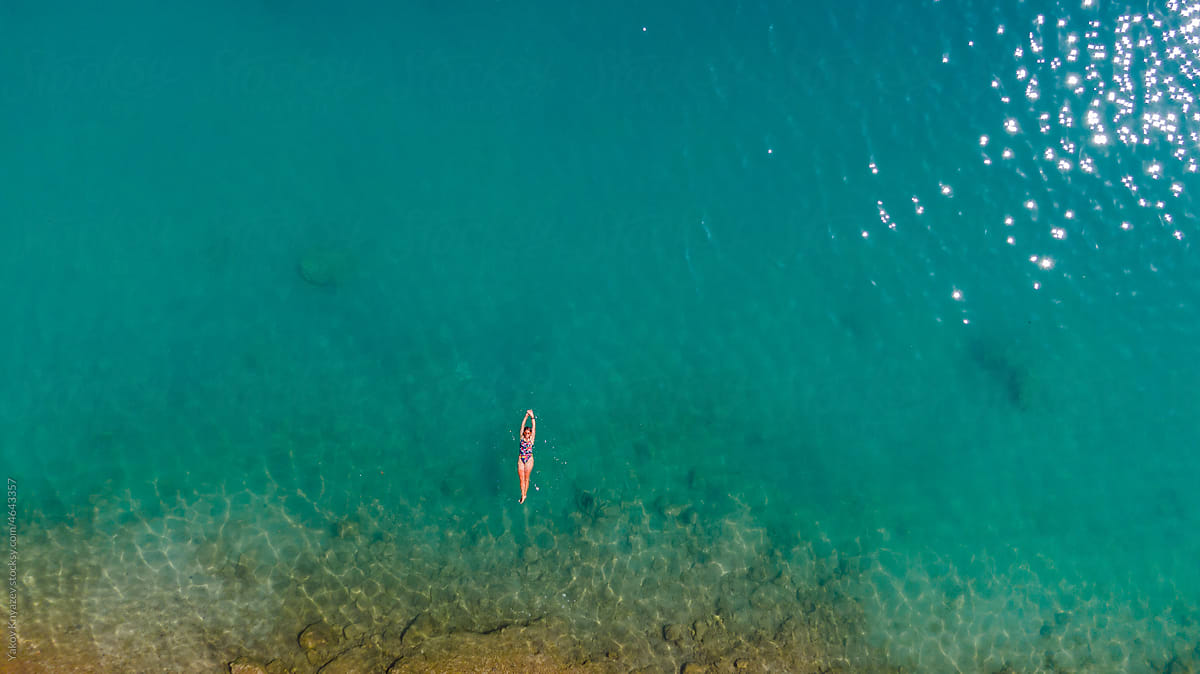 young woman in azure water, drone overhead