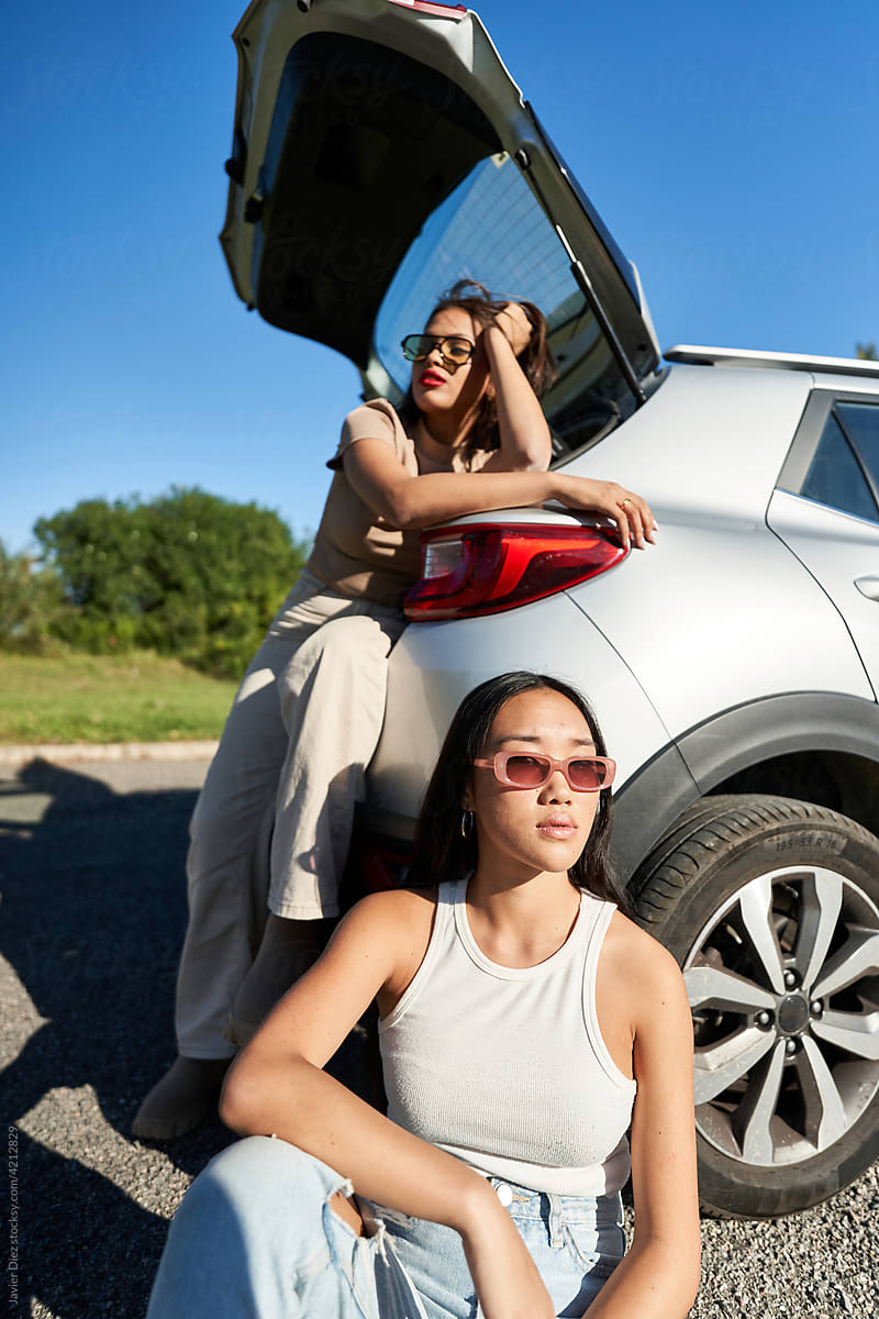 Diverse women sitting near SUV car