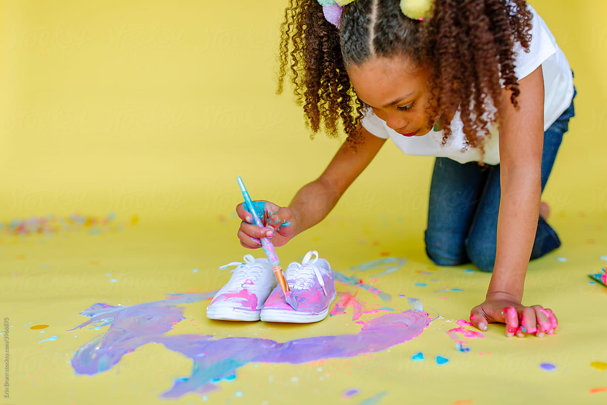 Adorable girl paints her shoes