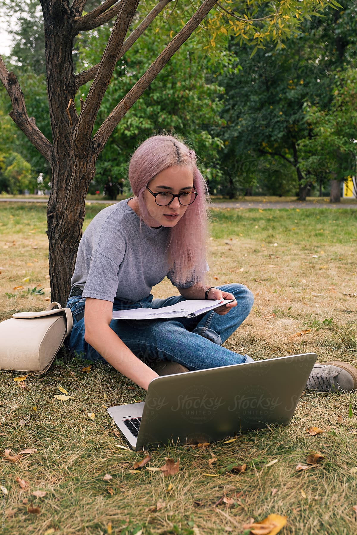 Clever pink-haired girl using laptop in park