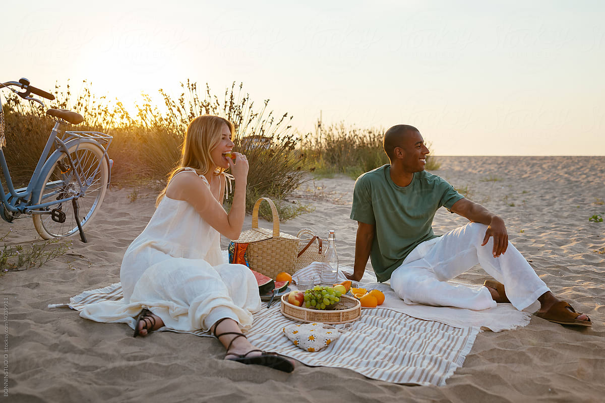 Young diverse couple having romantic picnic together