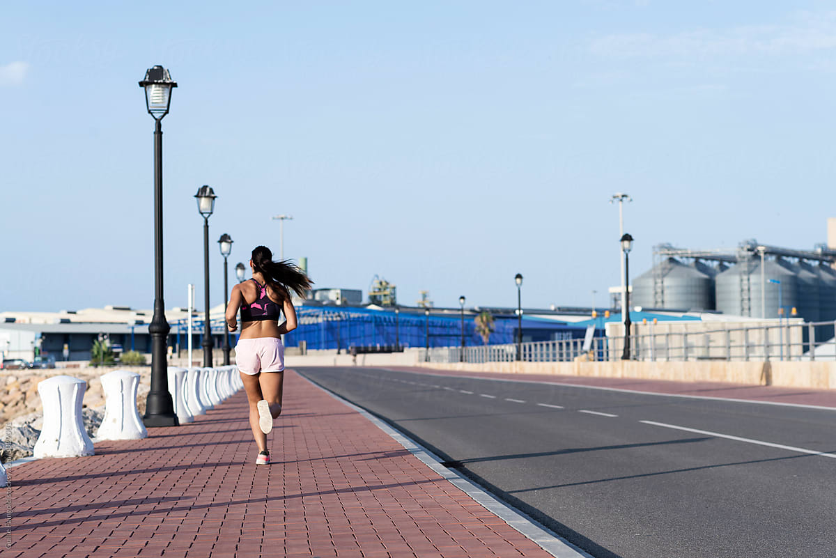 Athletic woman running along the road.
