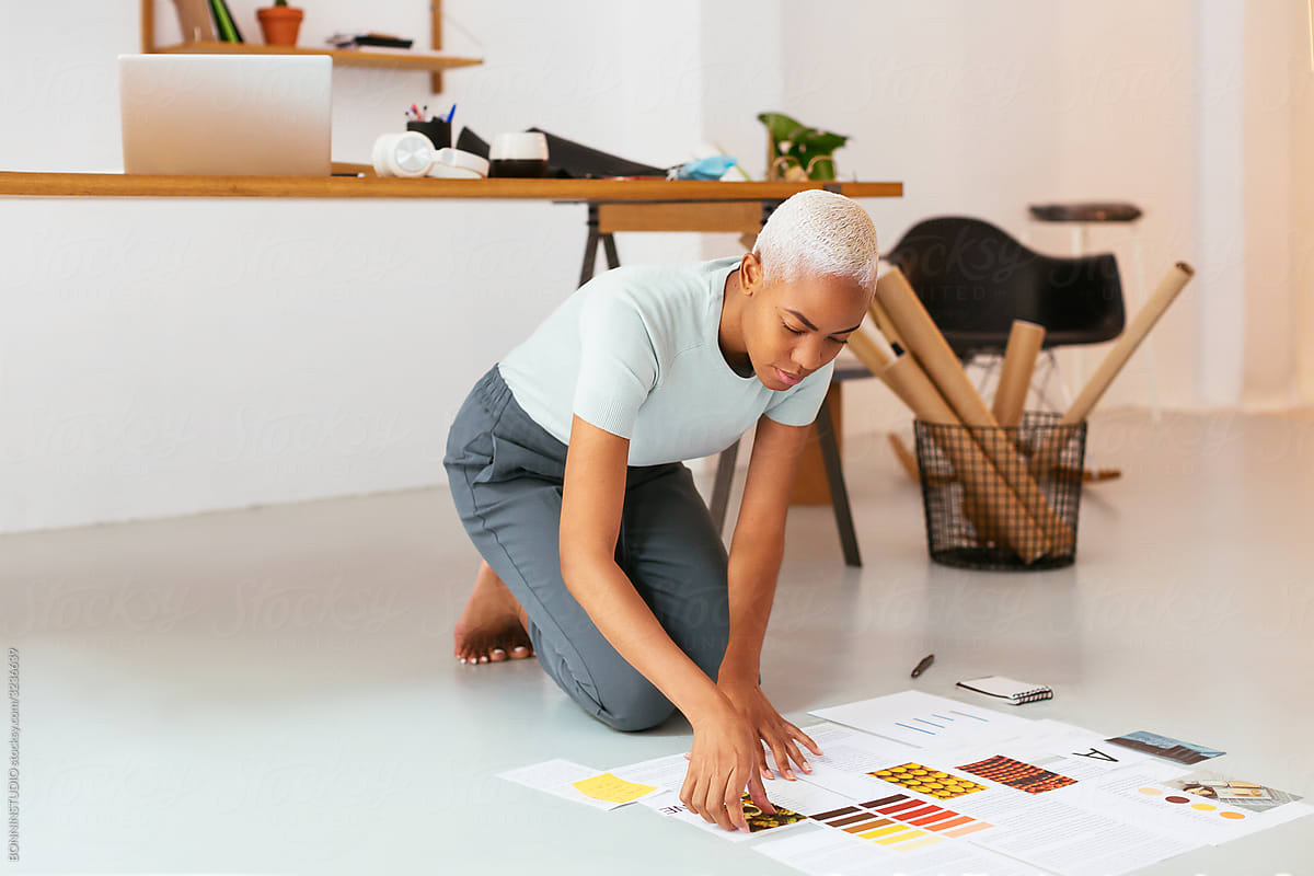 African American designer arranging papers on floor