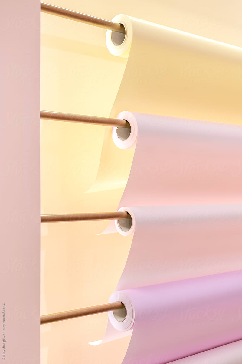 Four rolls of colourful paper hanging on the wall, close up