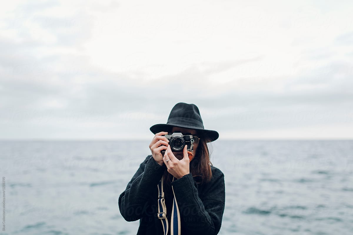 Woman with a black hat taking pictures with a vintage camera