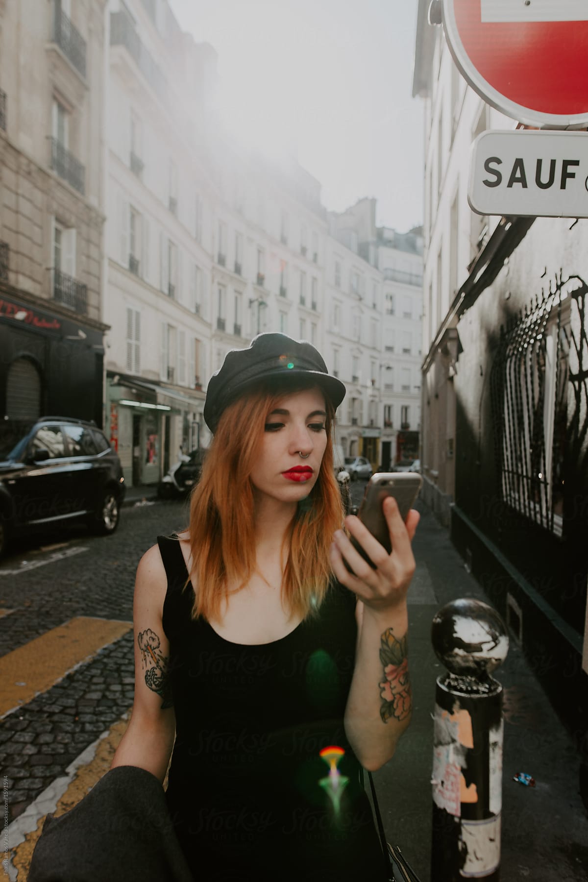 Ginger Woman Wearing A Hat Looking At His Phone In The Street By Stocksy Contributor Thais