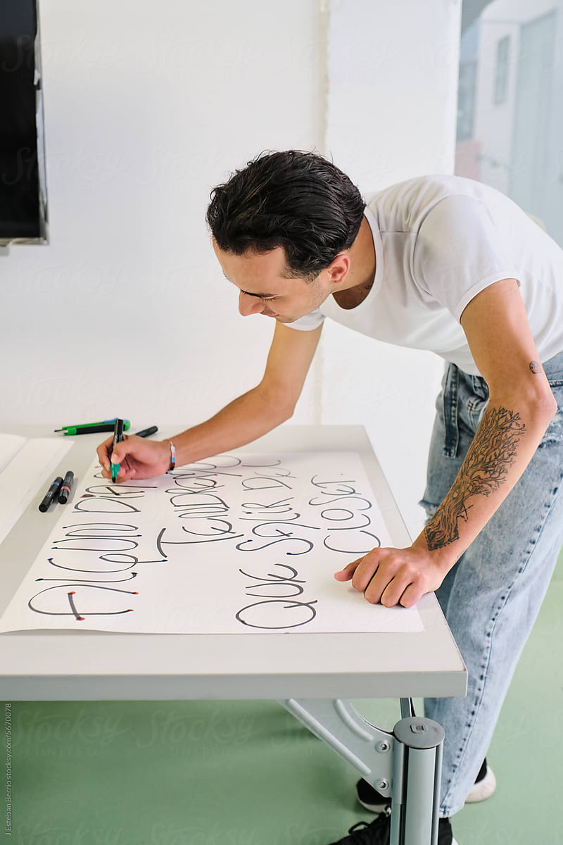 Latino man writes protest phrases on poster boards