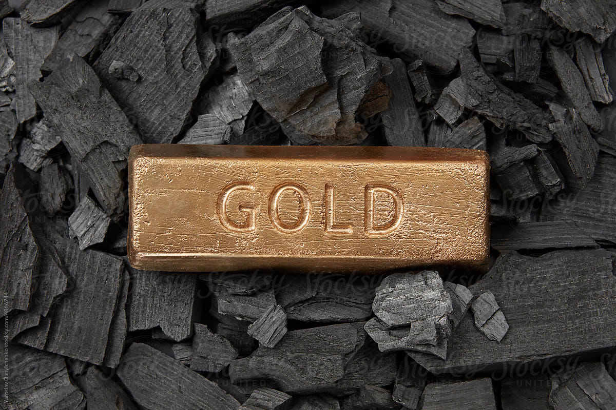 Golden bar on black coal, full frame.
