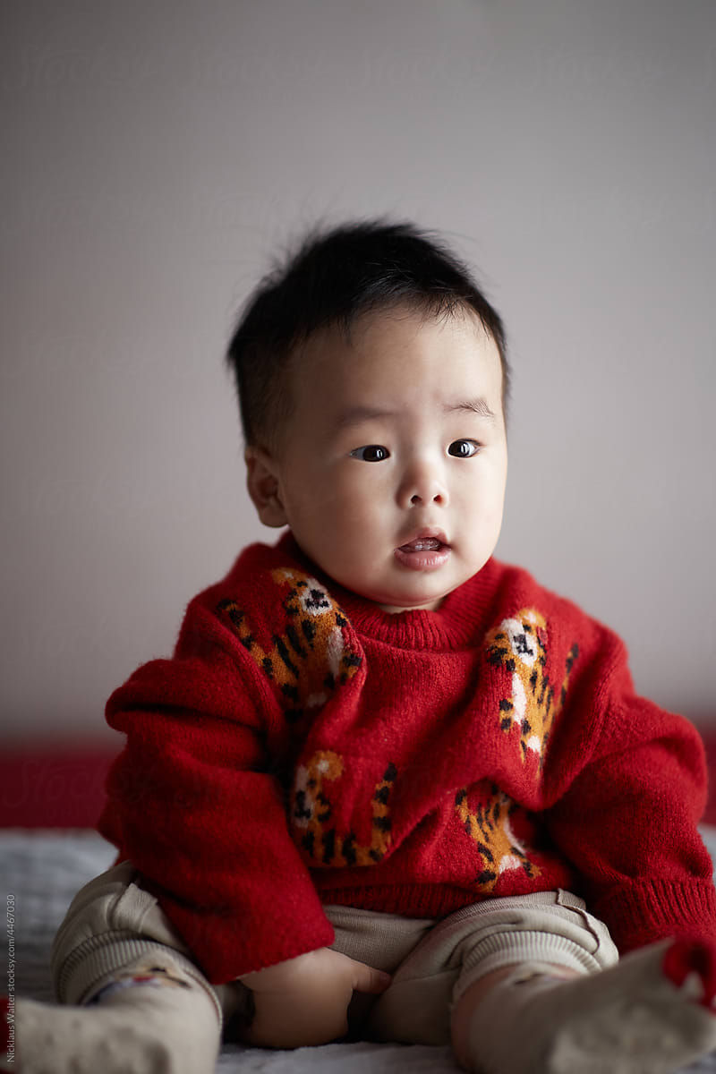 Cute Male Chinese Infant Sitting On A Bed At Home In Anhui, China.