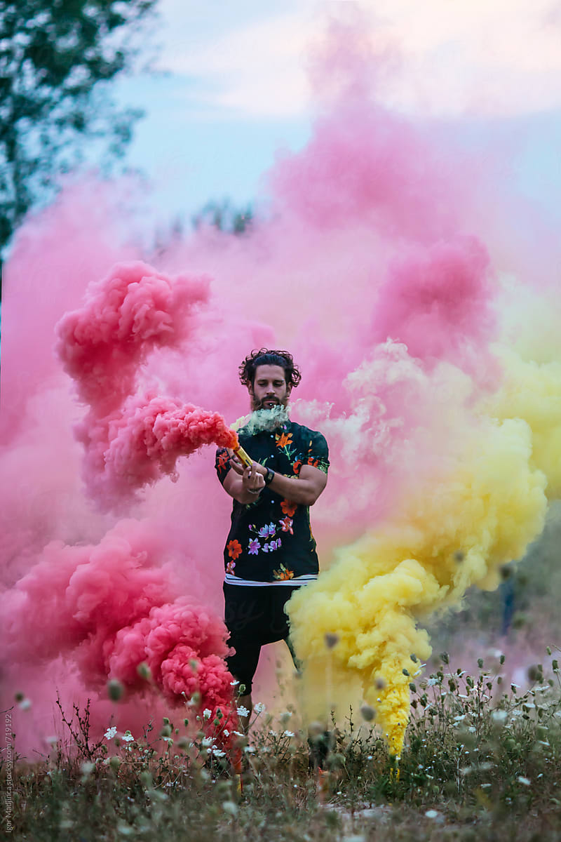 Fashionable Hipster Man Holding Colorful Smoke Bombs In Nature by Stocksy  Contributor Igor Madjinca - Stocksy