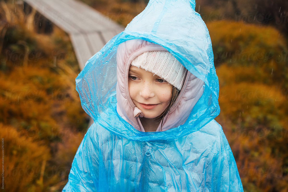 Close up of a young girl wearing a blue plastic poncho while hiking