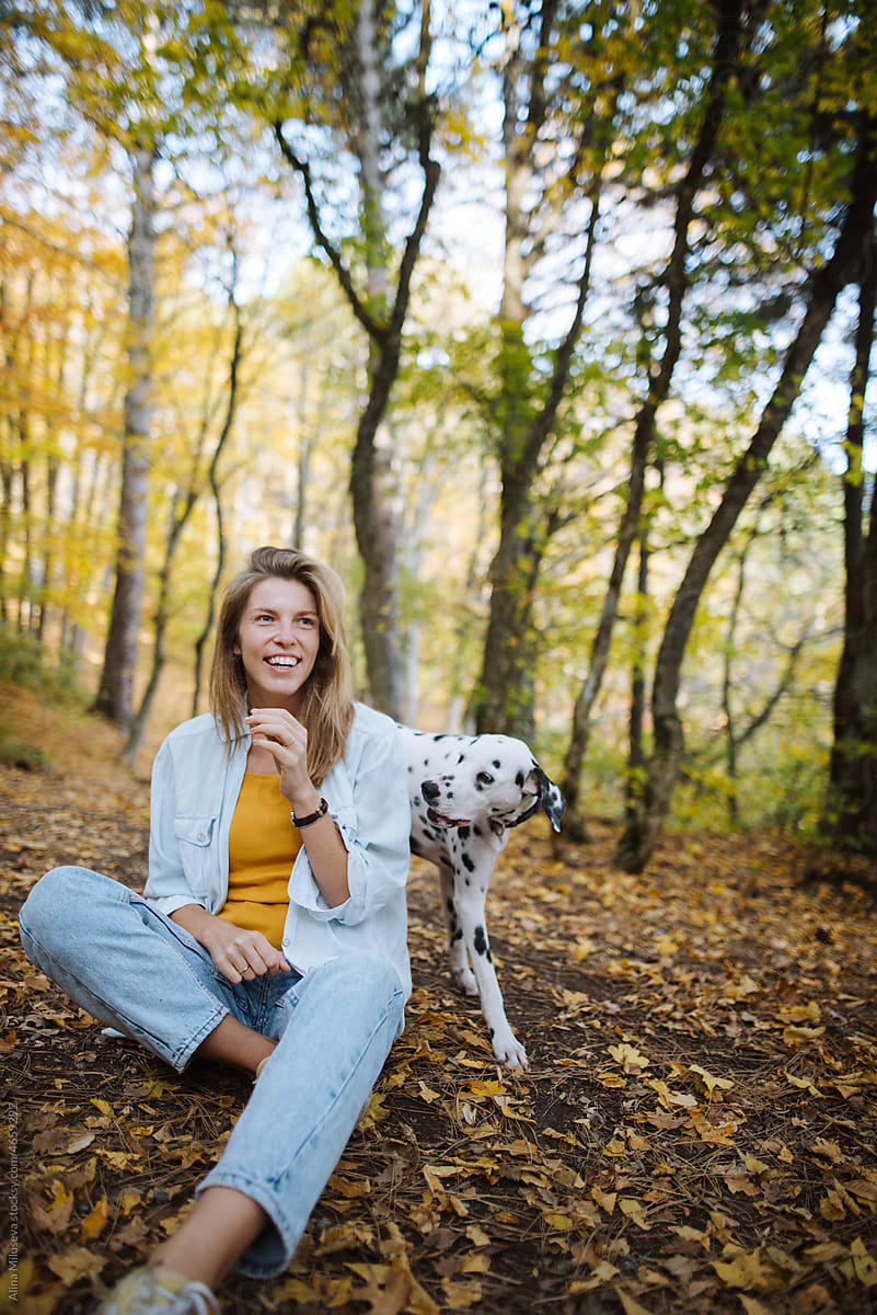 Happy woman with dog in park in fall season