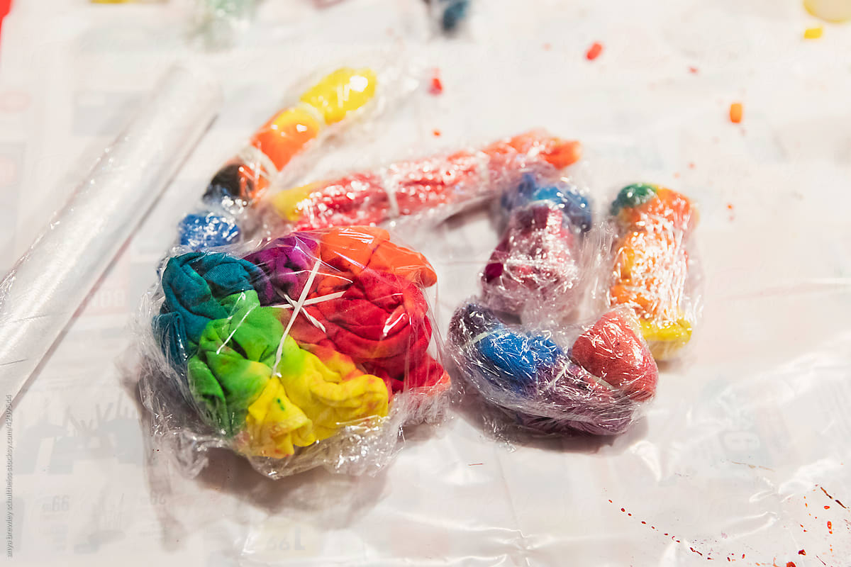 Pieces of tie dyed clothing wrapped in plastic wrap