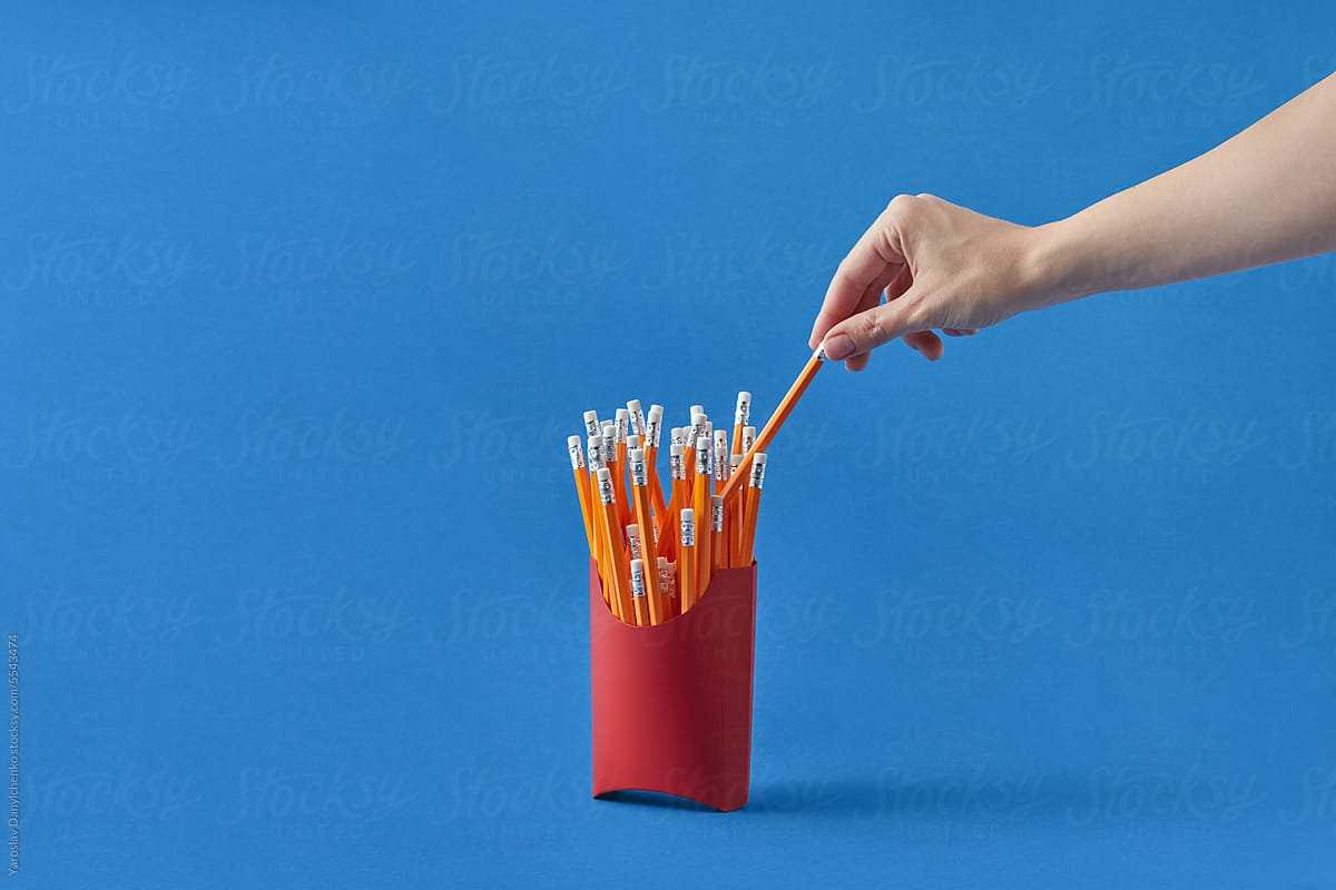 Female hand taking pencil from fries package.