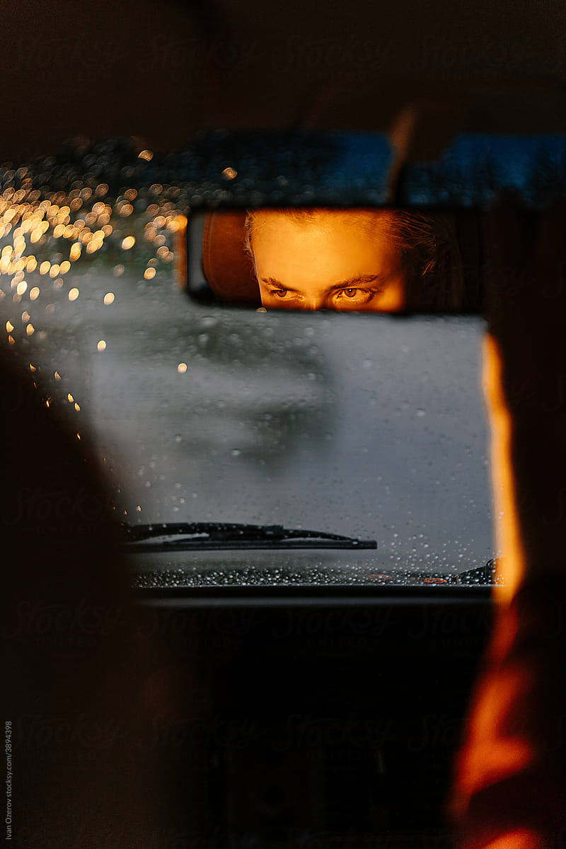 Woman reflecting in back mirror driving car
