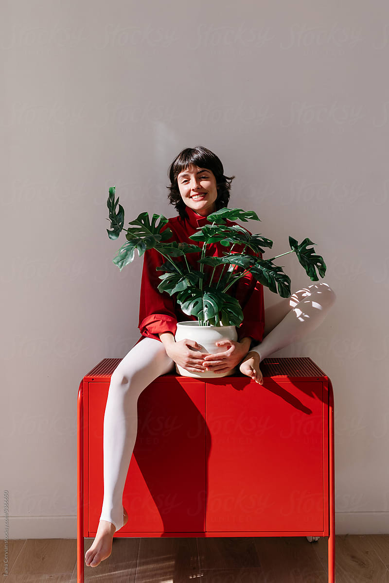 Cheerful woman holding potted plant
