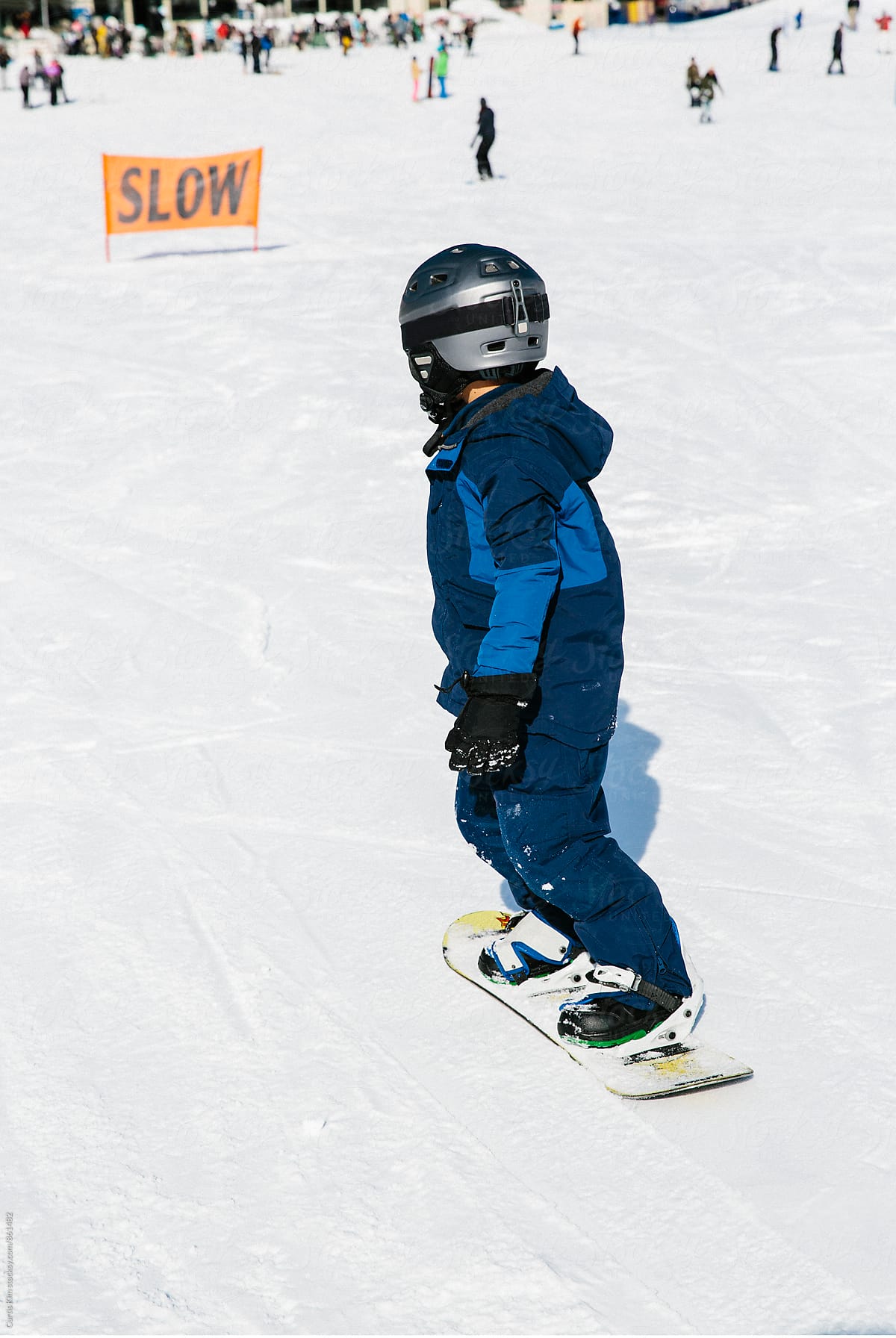 Young boy snowboarding down a hill
