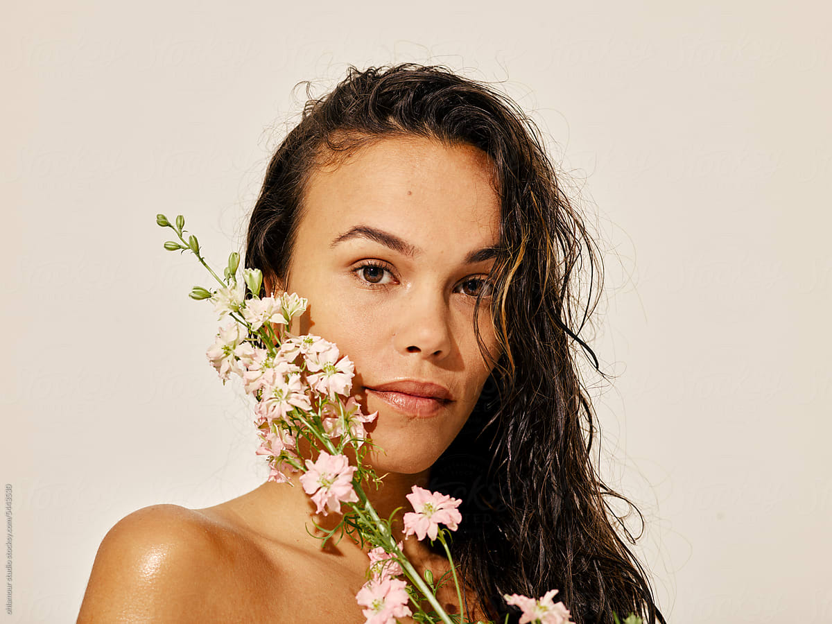 Woman with wet hair and bouquet of flowers, beauty studio portrait