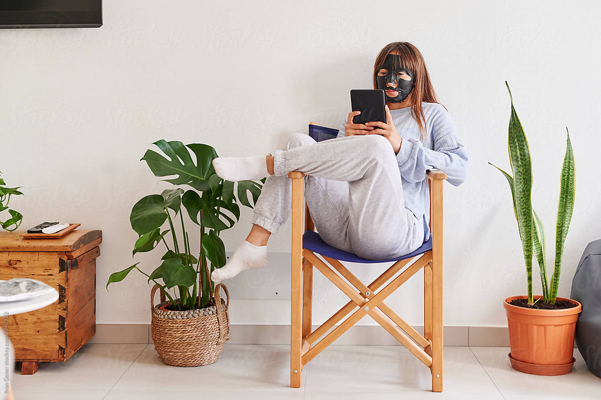 Woman wearing a facial mask reading at home