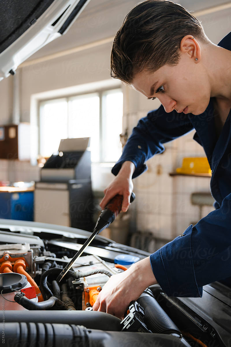 The woman repairs a car in the garage