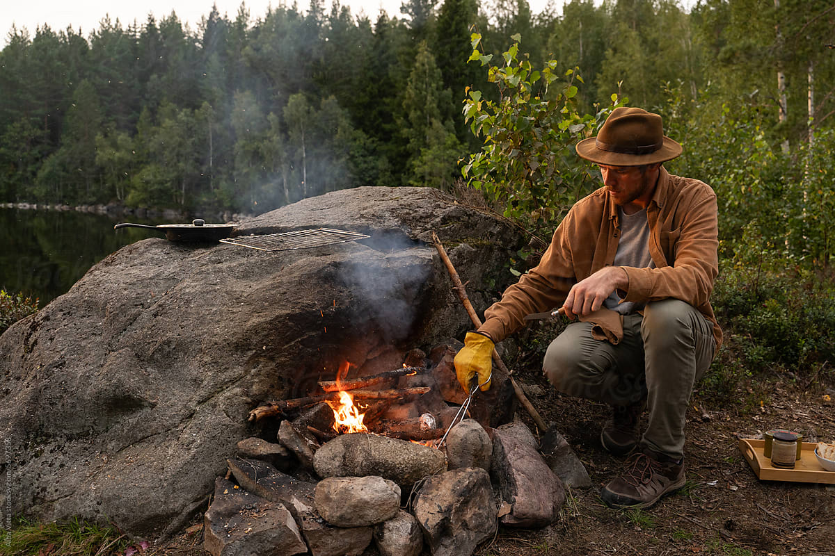 man cooking at bonfire